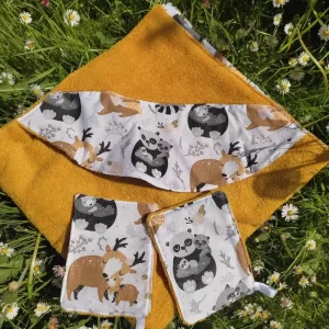 une cape de bain pliée en 4 posée sur de l'herbe avec des paquerettes.elle est de couleur ocre