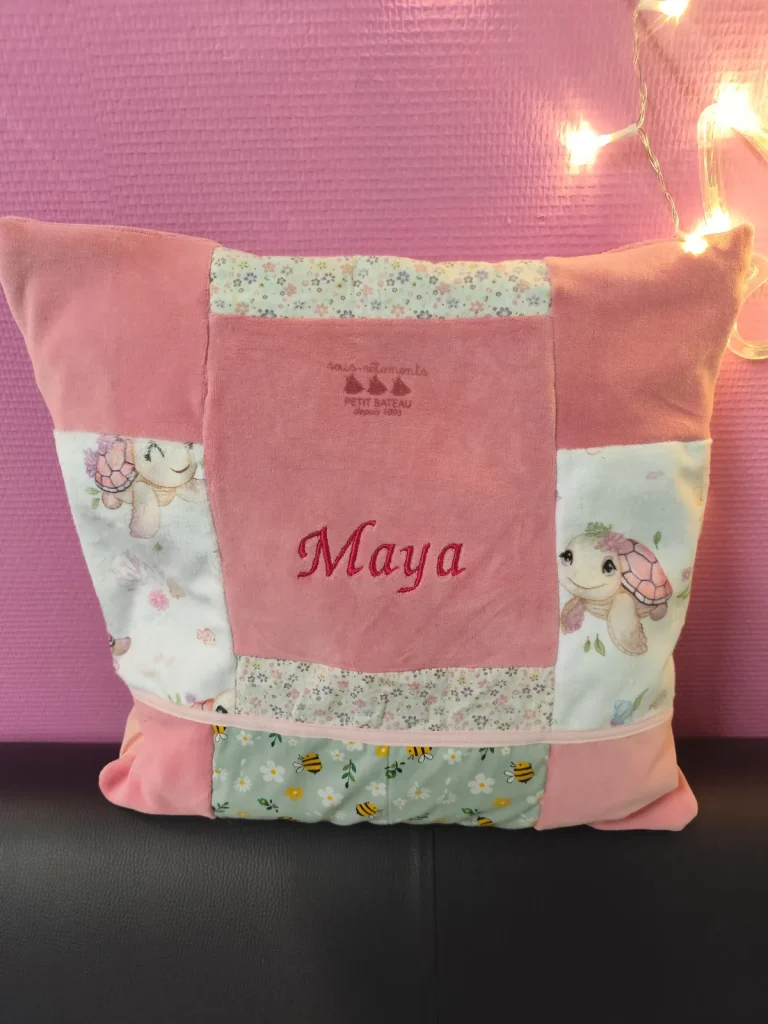 sur la photo pn peu voir un coussin rose fait avec les habits du bébé et il y a Maya brodé au centre