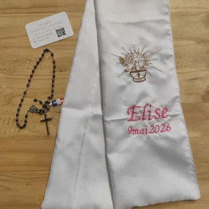 Sur la photo il y a une écharpe de baptême avec une broderie: un calice avec une crois dessus et une autre croix avec colombe.Il y a également le nom de la petite fille et la date de son baptême