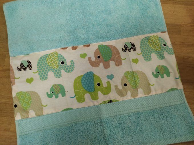linge en éponge verte bleu avec des éléphants verts et jaune,bleus comme motif sue le coton cous dessus