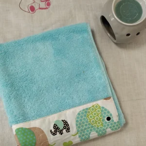 photo linge en éponge verte bleu avec des éléphants verts et jaune,bleus comme motif sue le coton cous dessus