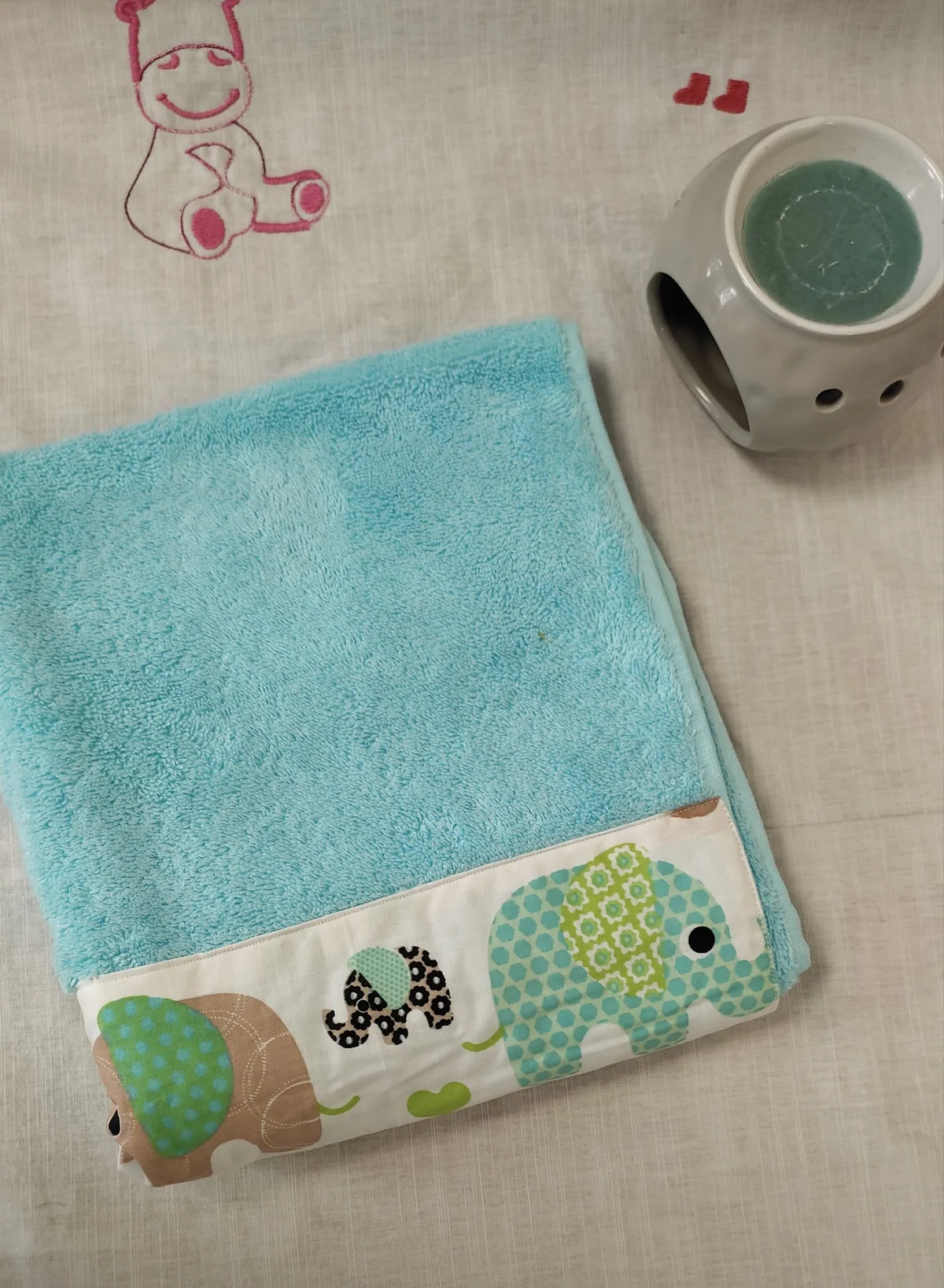 photo linge en éponge verte bleu avec des éléphants verts et jaune,bleus comme motif sue le coton cous dessus