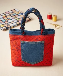 sac rouge et jeans poser sur une table,il est fabriqué avec de la dentelle et une poche en jeans devant