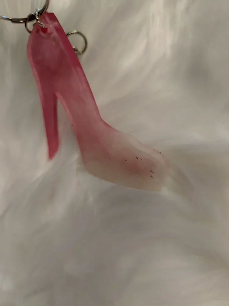 Porte clé chaussure talon haut posé sur un tapis blanc