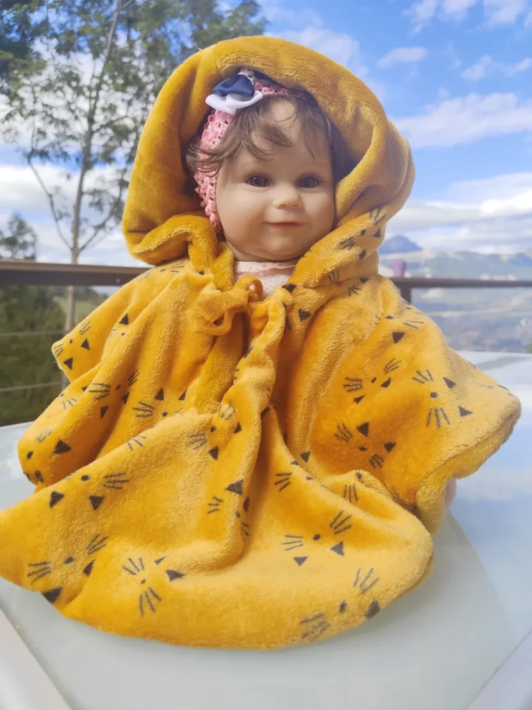 bébé posé sur une table,il porte une cape polaire réversible jaune