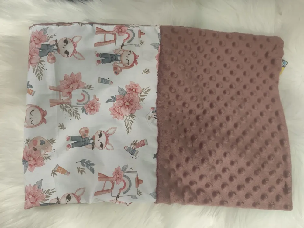 couverture posée sur le bureau .cette couverture et un coté minky et de l'autre du coton avrc des personnage souris un peu style ancien