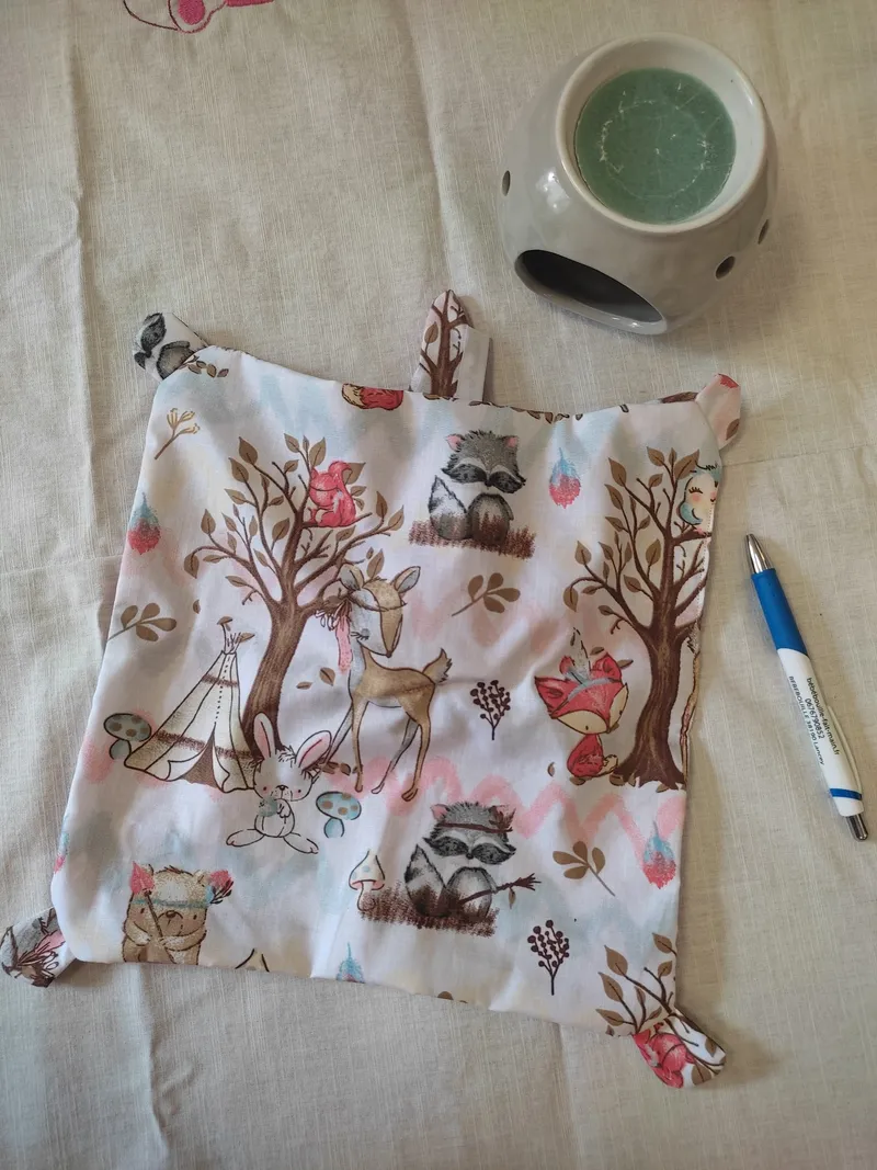arrière du doudou lapin rose.C'est un carré de coton blanc avec les animaux de la forêt